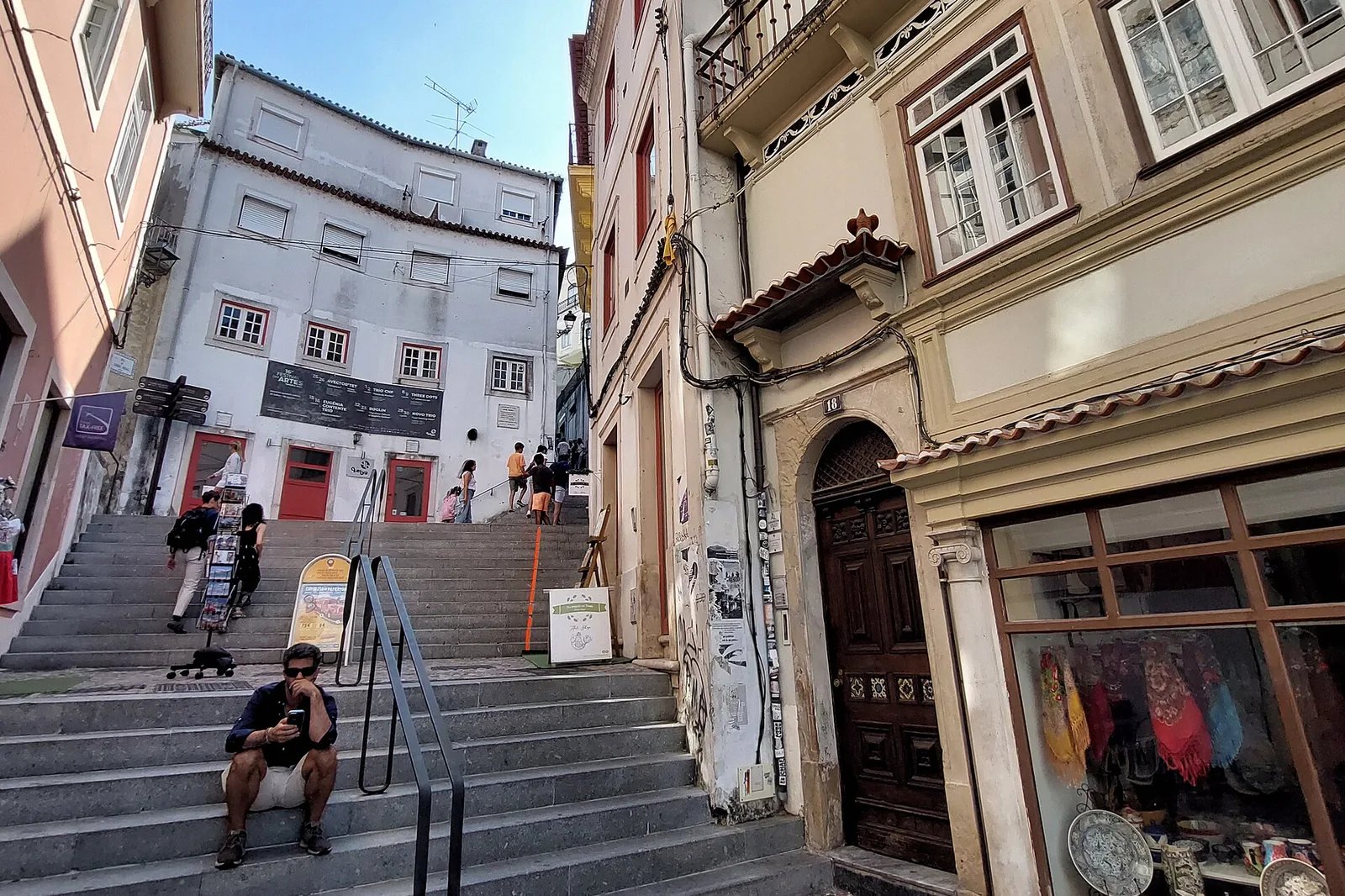 Besucher steigen eine Treppe zwischen hohen gefliesten Gebäuden in der Rua de Quebra-Costas hinauf